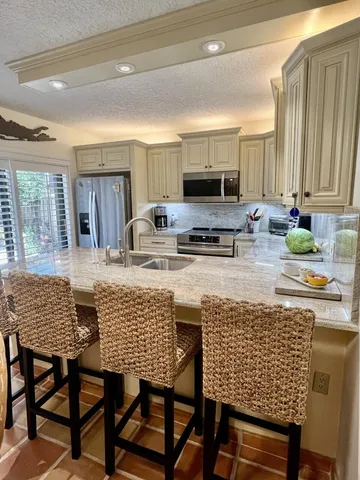 a kitchen with kitchen island granite countertop a table chairs sink and cabinets