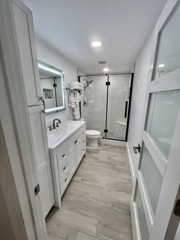 a bathroom with a sink a toilet a mirror and shower