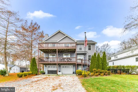 a front view of a house with a garden and tree