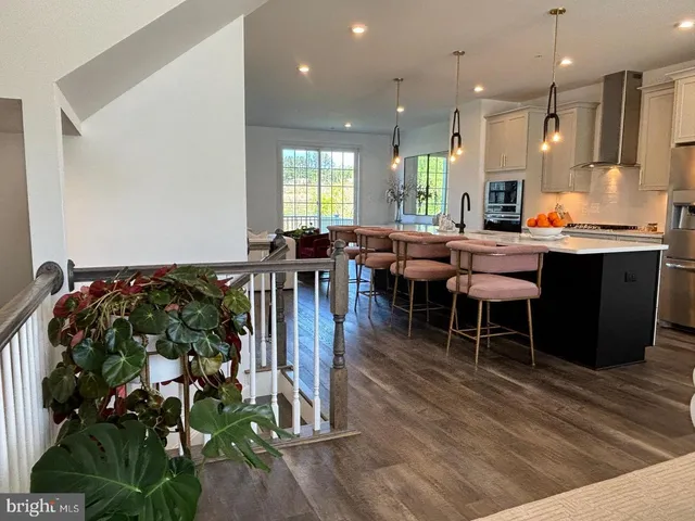 a large dining hall with stainless steel appliances granite countertop a stove a sink a dining table and chairs with wooden floor