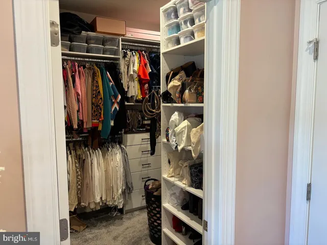 a view of walk in closet with clothes and shoes