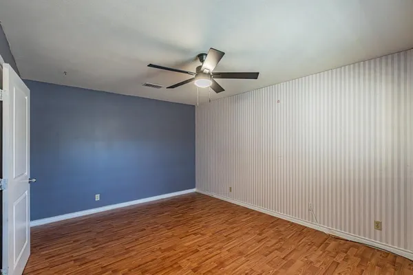 a view of empty room with wooden floor and fan