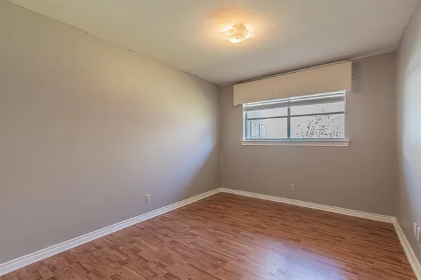 a view of an empty room with wooden floor and a ceiling fan