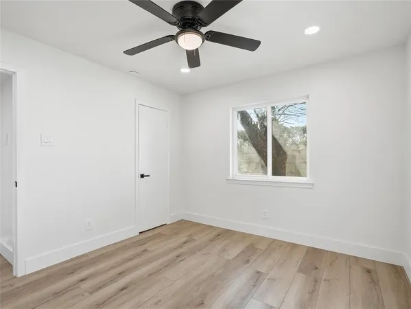 an empty room with a window and a fan