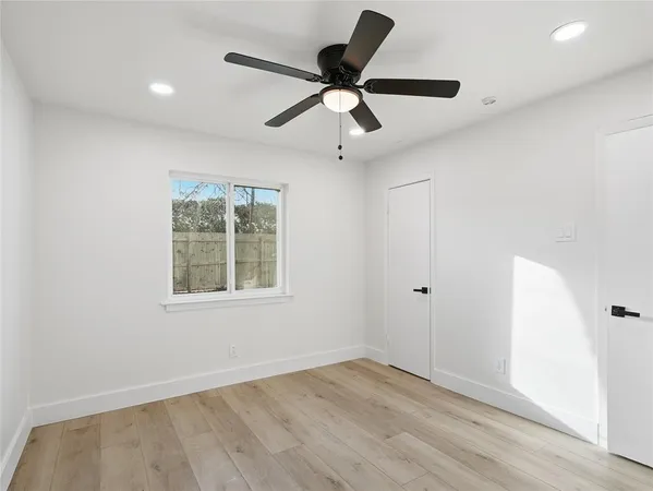 an empty room with wooden floor ceiling fan and windows