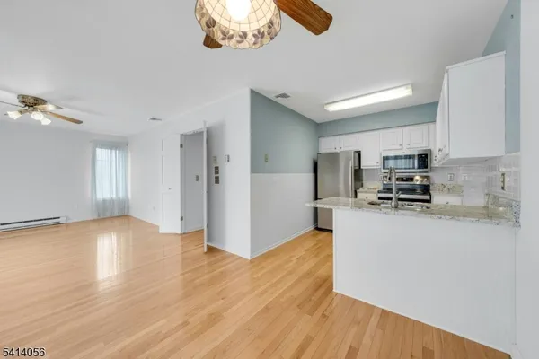 a kitchen with granite countertop a sink a stove a refrigerator and white cabinets