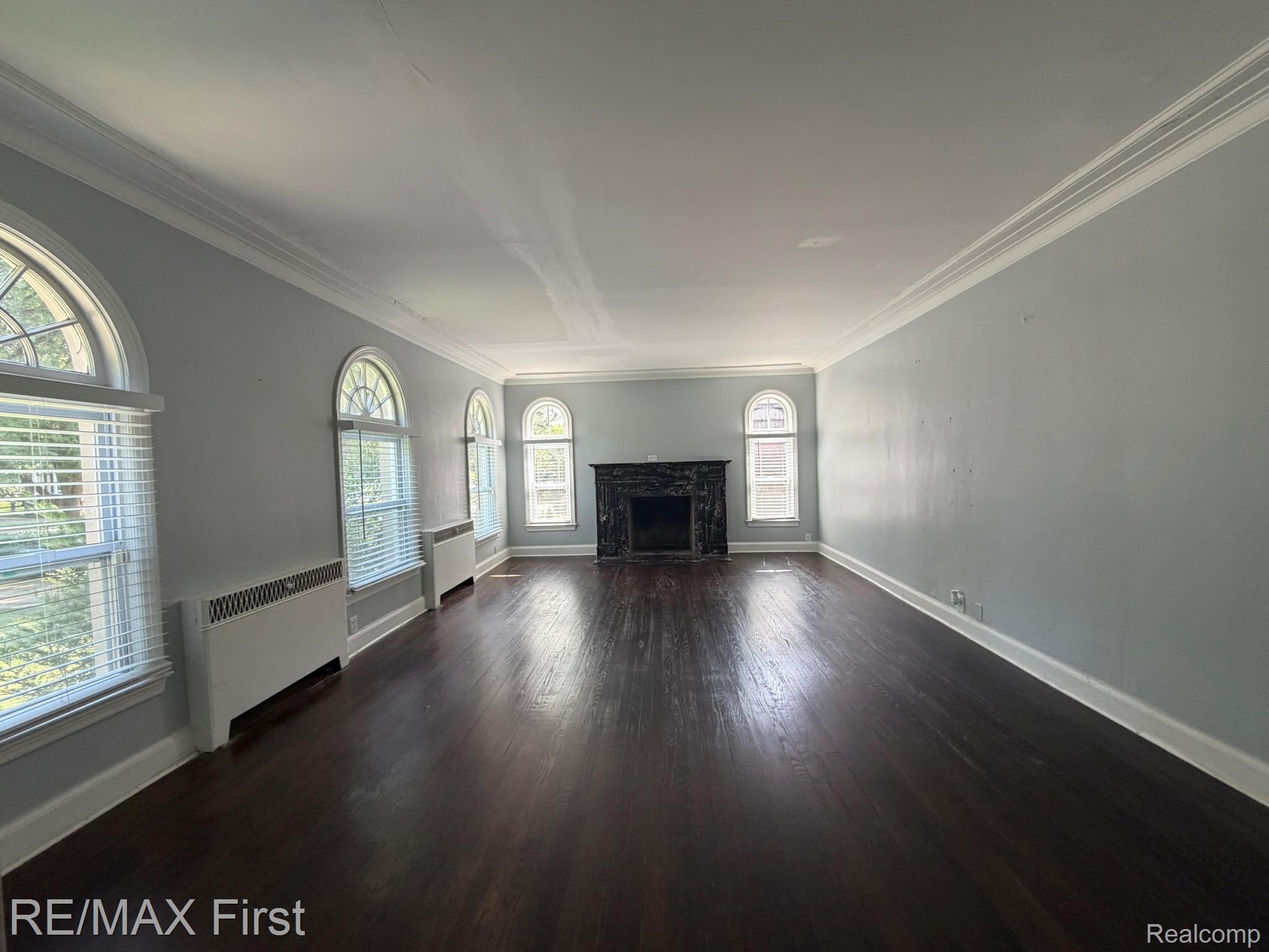1349 Devonshire Road Grosse Pointe, MI 48230 - Photo 7 of 31 Hardwood flooring, arched windows, crown molding, and a dark stone fireplace surround
