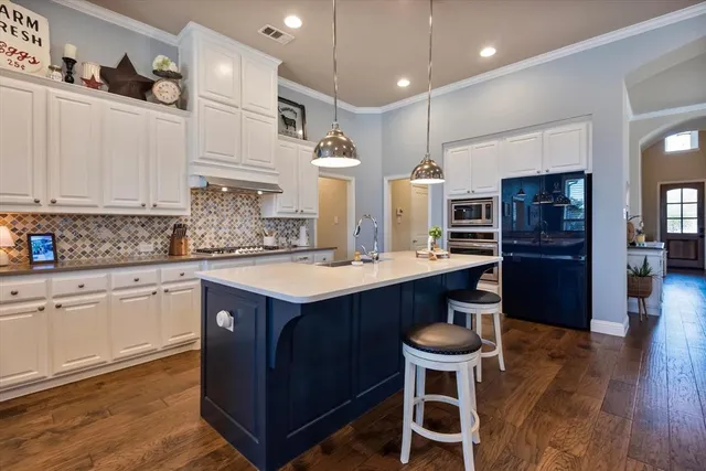 a kitchen with stainless steel appliances kitchen island granite countertop a table chairs sink and cabinets