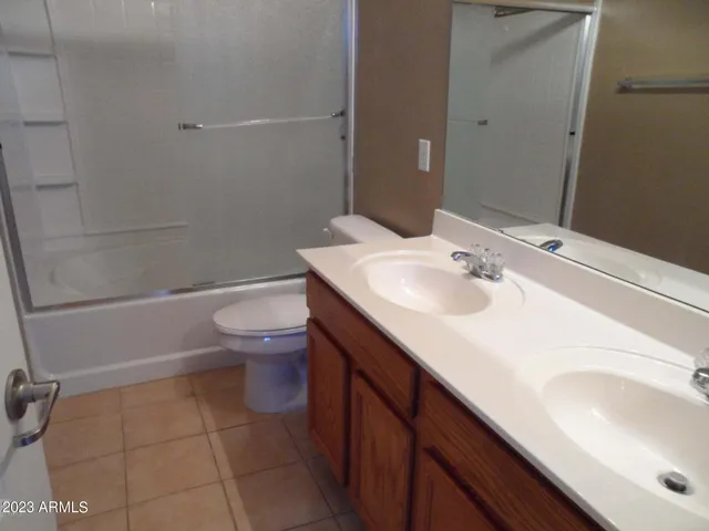 an empty room with a chandelier fan and windows