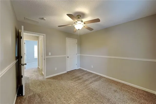 an empty room with closet and a chandelier fan