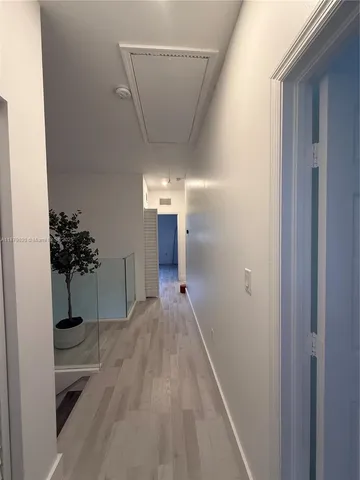 a view of a hallway with wooden floor and a potted plant