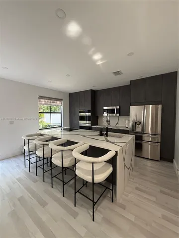 a kitchen with a dining table chairs and refrigerator