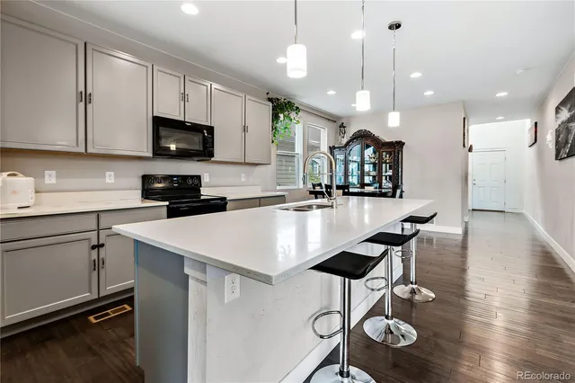 a kitchen with stainless steel appliances kitchen island granite countertop a stove a sink a dining table and chairs with wooden floor