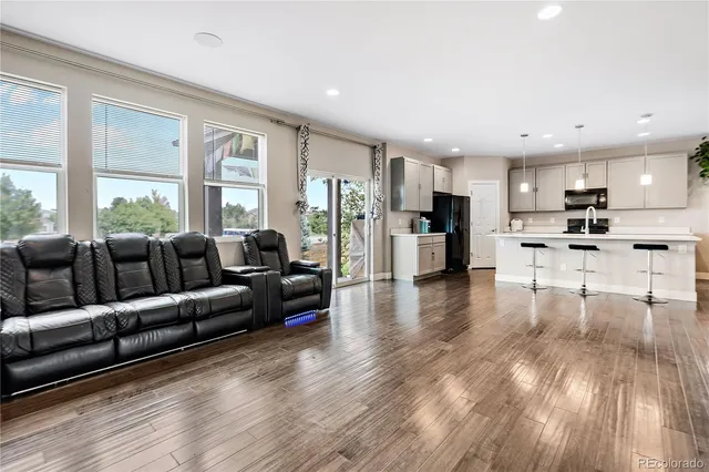 a living room with furniture and kitchen view with wooden floor