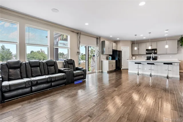 a living room with furniture and kitchen view with wooden floor