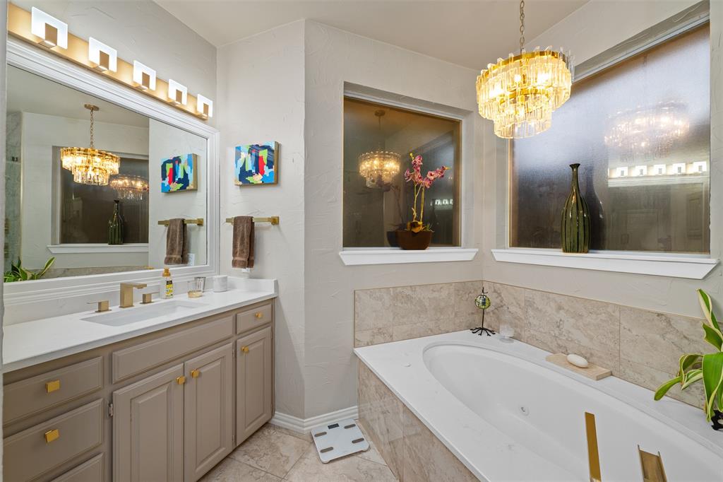 17608 Windflower Way Dallas, TX 75252 - Photo 21 of 34 Bathroom with a chandelier, a whirlpool tub, vanity, and light tile patterned floors
