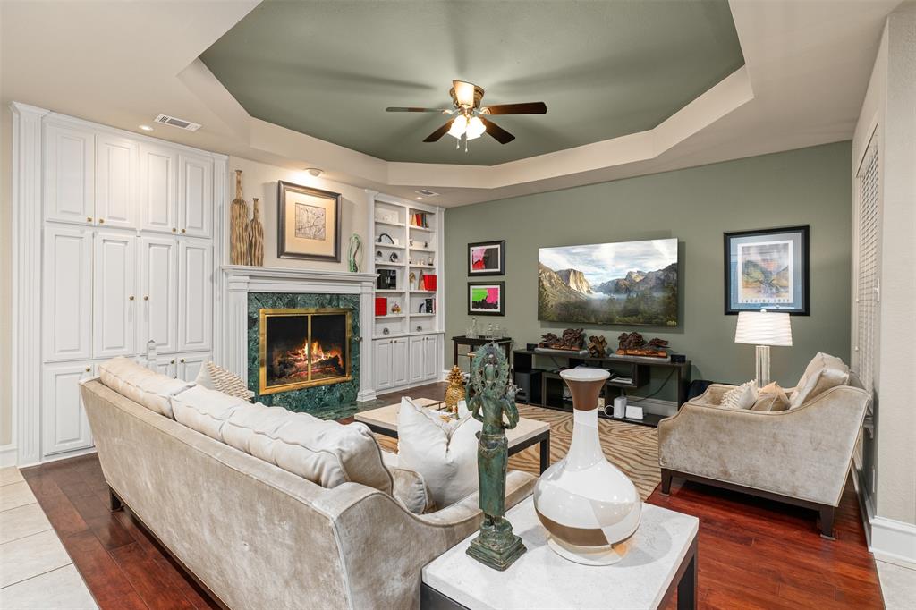 17608 Windflower Way Dallas, TX 75252 - Photo 5 of 34 Living room with a raised ceiling, a premium fireplace, ceiling fan, and dark wood-type flooring