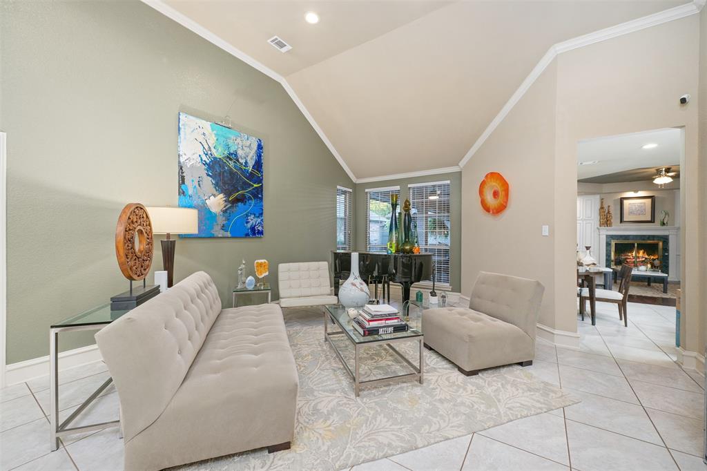 17608 Windflower Way Dallas, TX 75252 - Photo 7 of 34 Living area featuring crown molding, a tile fireplace, light tile patterned floors, recessed lighting, and lofted ceiling