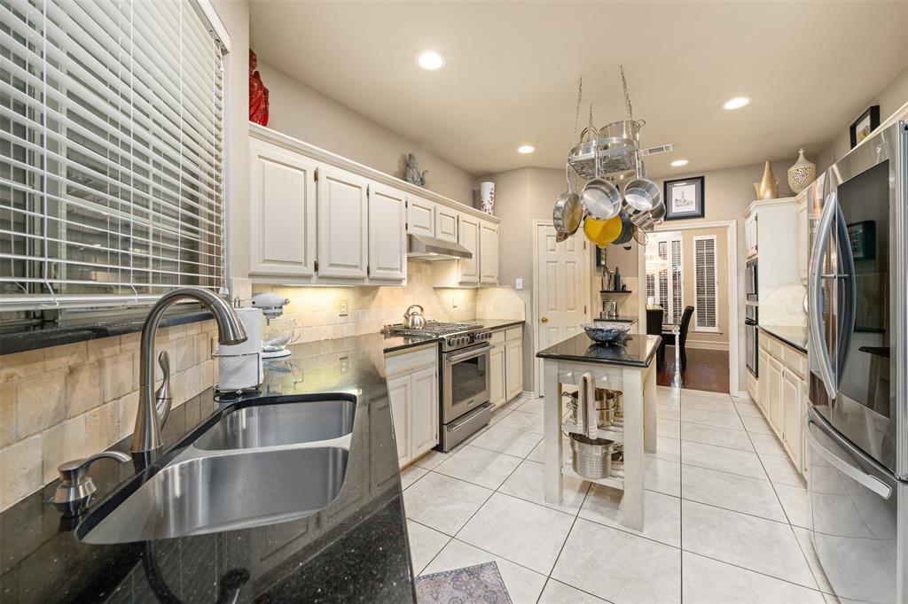 17608 Windflower Way Dallas, TX 75252 - Photo 10 of 34 Kitchen featuring backsplash, appliances with stainless steel finishes, light tile patterned floors, recessed lighting, and dark stone countertops
