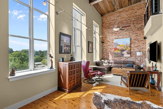 a living room with furniture a flat screen tv and a floor to ceiling window