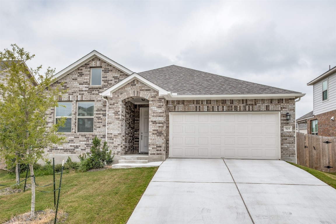 View of front of home with brick siding, roof with shingles, driveway, and a garage