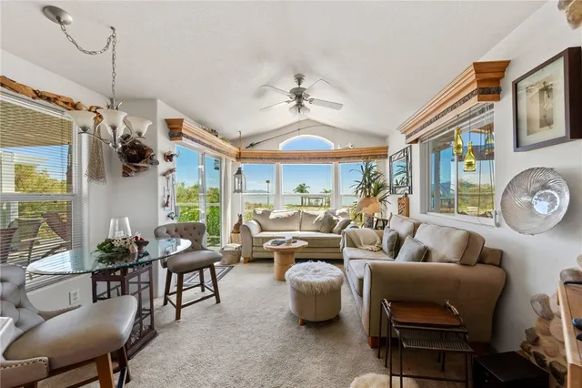 a living room with furniture a ceiling fan and a large window