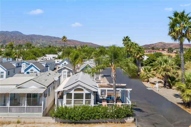 a front view of a house with a yard and mountain view in back