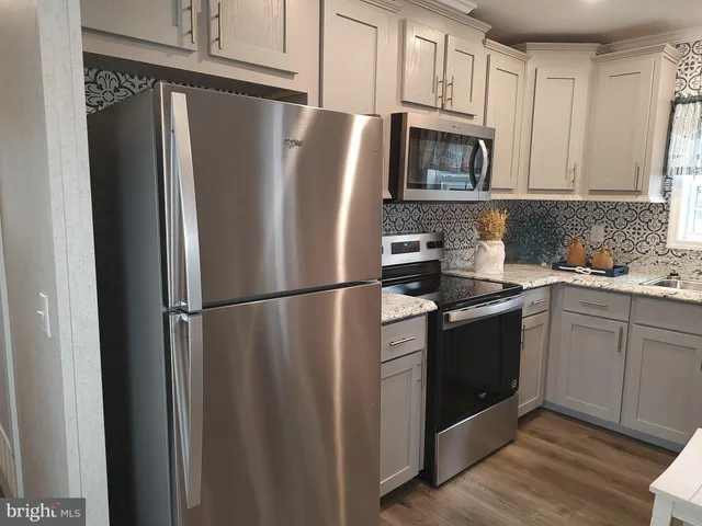 a kitchen with stainless steel appliances granite countertop a refrigerator stove a sink and dishwasher with wooden floor