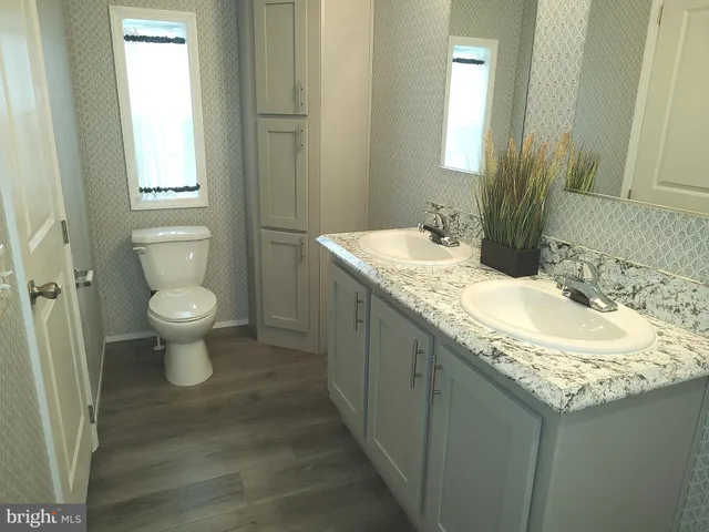a bathroom with a granite countertop sink a toilet and a mirror