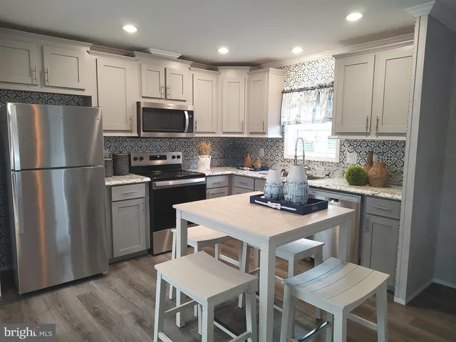 a kitchen with a sink a stove a refrigerator and white cabinets with wooden floor