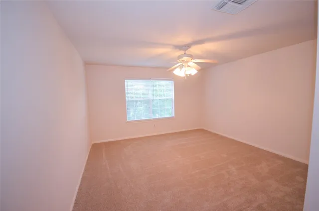 an empty room with windows and fan