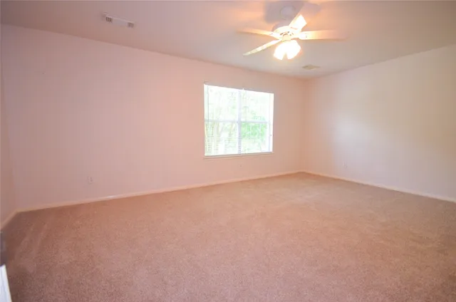 an empty room with a window and a ceiling fan