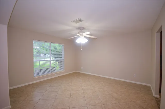an empty room with windows and chandelier fan