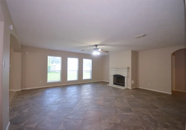an empty room with windows and fireplace