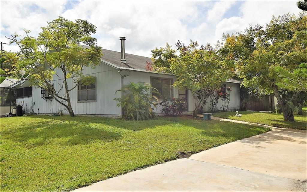 a backyard of a house with plants and large trees