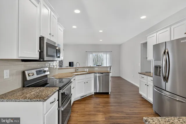 a kitchen with stainless steel appliances granite countertop a sink stove microwave and refrigerator