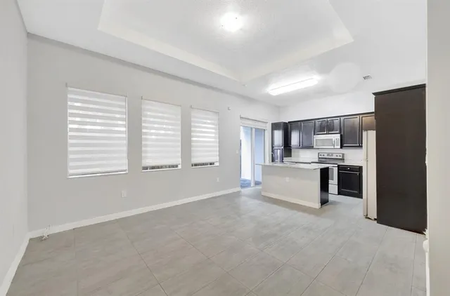 a large white kitchen with kitchen island a sink stainless steel appliances and cabinets