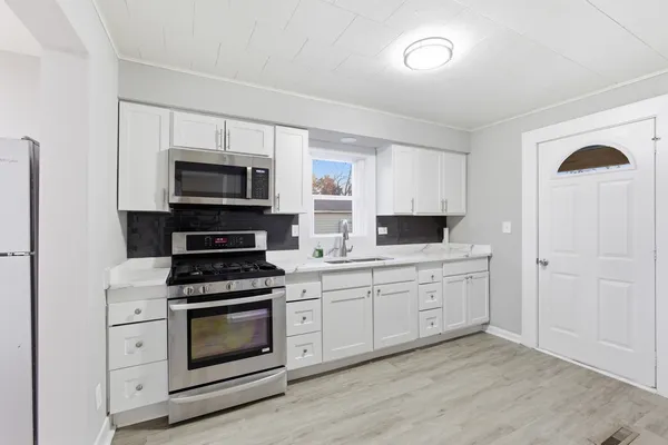 a kitchen with cabinets stainless steel appliances and wooden floor