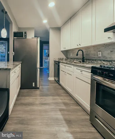 a kitchen with granite countertop a sink stove and refrigerator