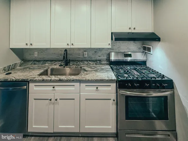 a kitchen with granite countertop white cabinets and stainless steel appliances