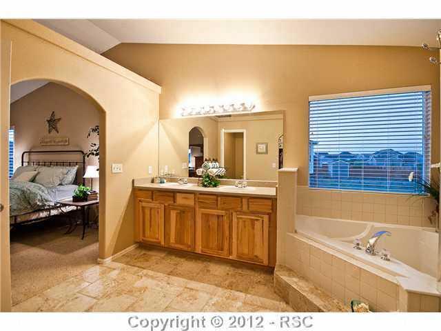 8739 Del Rio Road Peyton, CO 80831 - Photo 13 of 25 A decorative archway leads to the elegant 5-piece Master Bath that has Travertine–look tile floors and raised hickory vanity w/dual sinks and brushed nickel hardware