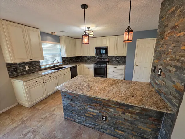 a kitchen with stainless steel appliances kitchen island granite countertop a stove a sink and a refrigerator