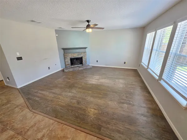 an empty room with windows and fireplace