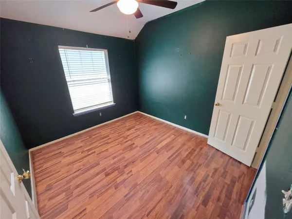a view of an empty room with window and wooden floor