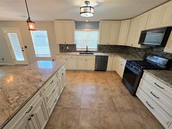 a kitchen with granite countertop a sink a counter space cabinets and stainless steel appliances