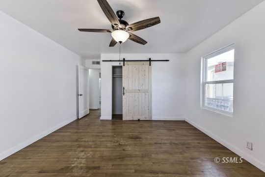 329 North Balsam Street Ridgecrest, CA 93555 - Photo 25 of 27 a view of an empty room with wooden floor and a ceiling fan