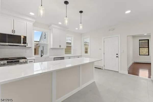 a large white kitchen with kitchen island a sink a stove a refrigerator and white cabinets