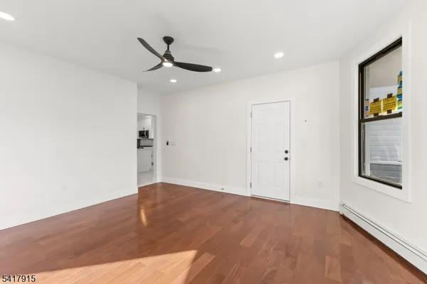 a view of an empty room with wooden floor and a window
