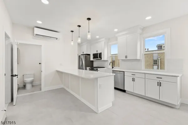 a large white kitchen with center island and stainless steel appliances