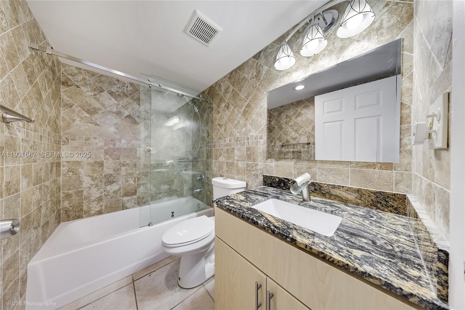 4301 Collins Avenue, Unit 803 Miami Beach, FL 33140 - Photo 17 of 25 a bathroom with a granite countertop sink a toilet a mirror and bathtub